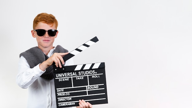 Free photo cool young child holding clapperboard