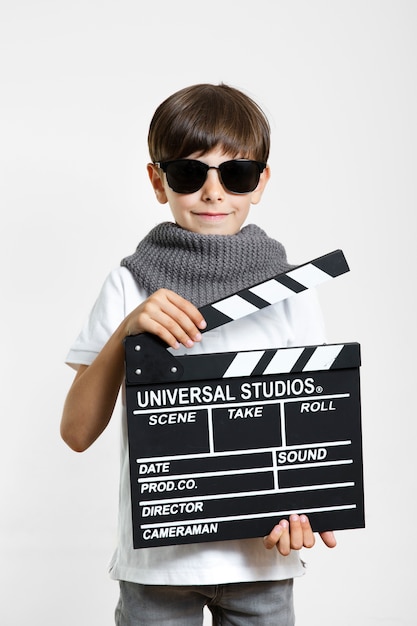 Free photo cool young child with sunglasses and clapperboard