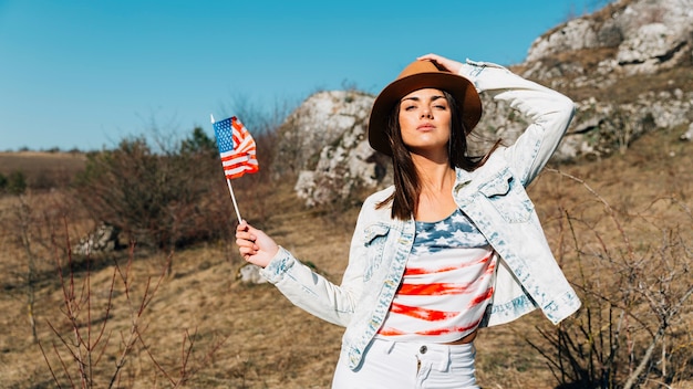 Cool young woman with USA flag posing in nature 