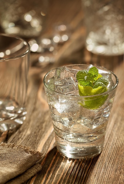 Copo de gin tônica com limão e gelo sobre uma mesa de madeira. Fechar-se. Ainda vida. Copiar espaço