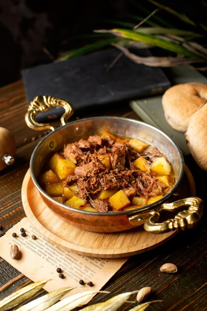 Медная сковорода с картофелем и тушеным мясом, приготовленная в масле
