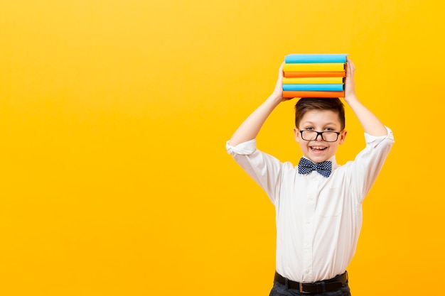 Бесплатное фото Копией пространства мальчик держит стопку книг