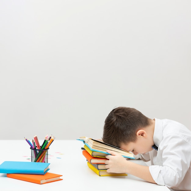 Free photo copy-space boy sitting with head on books