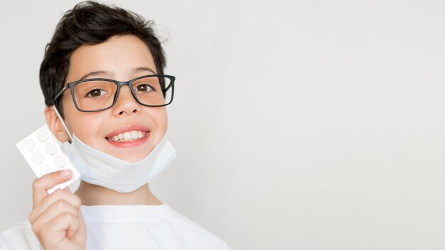 Copy-space boy with mask holding pills tablet