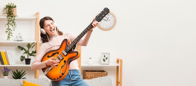 Free photo copy-space female on couch with guitar