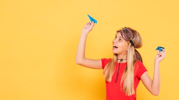 Copy-space girl playing with paper airplane