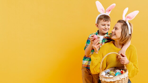 Copy-space mom and son with basket full of painted eggs