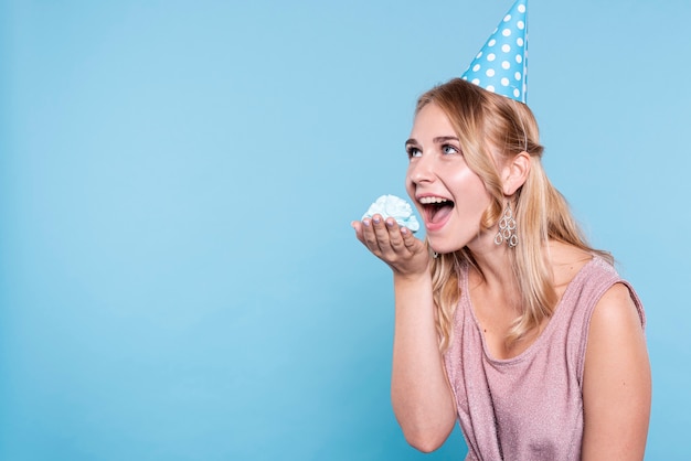 Free photo copy-space playful woman eating cake