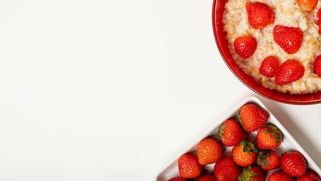 Copy space porridge with strawberries on plain background