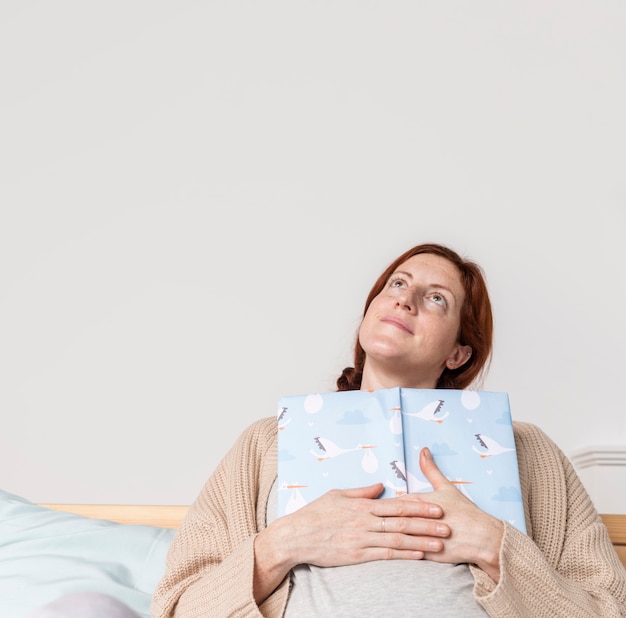 Free photo copy-space pregnant woman reading baby books