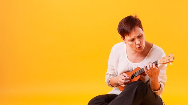Copy-space senior woman playing guitar