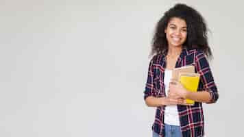 Foto gratuita ragazza di smiley copia-spazio con una pila di libri