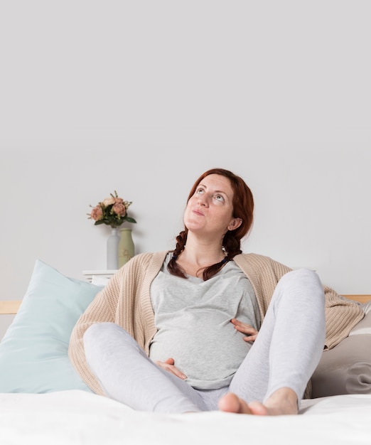 Copy-space woman pregnant at home in bed