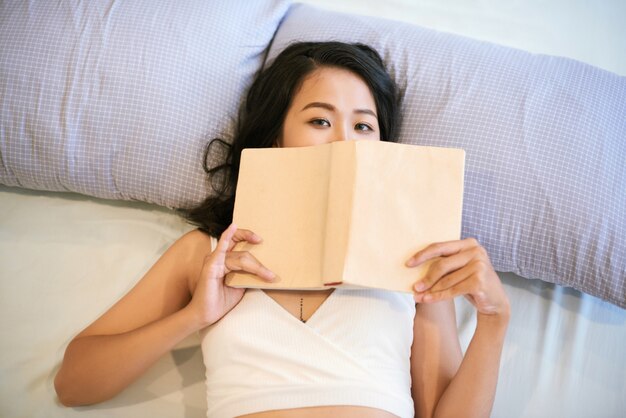 Coquette woman with book in bed
