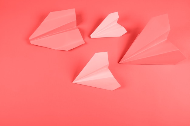 Coral and pink paper airplane on colored background