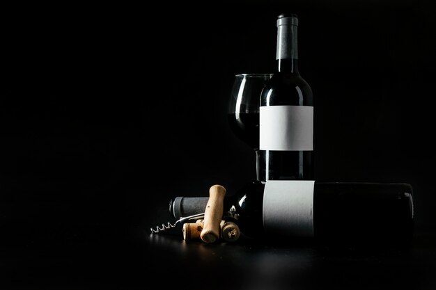 corkscrew and corks near bottles and wineglass
