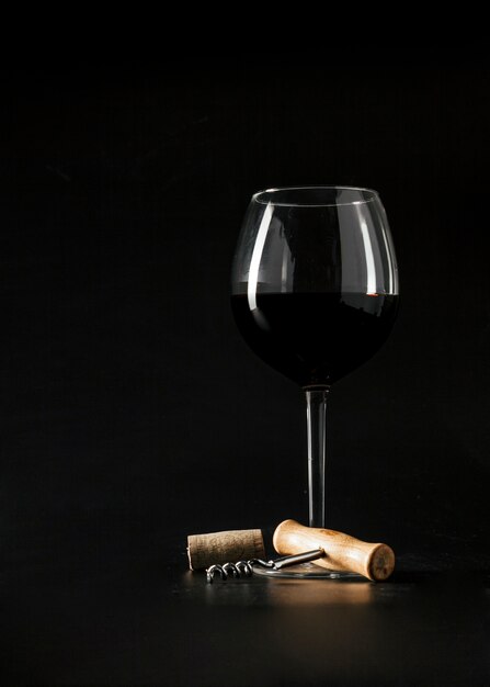 Corkscrew near glass of wine