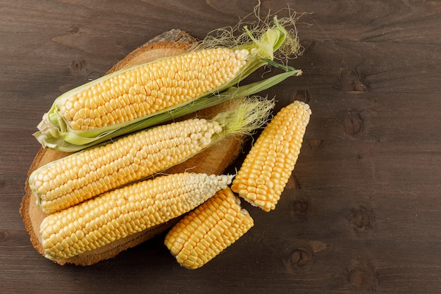 Corn cobs on a wooden piece on a wooden table. top view