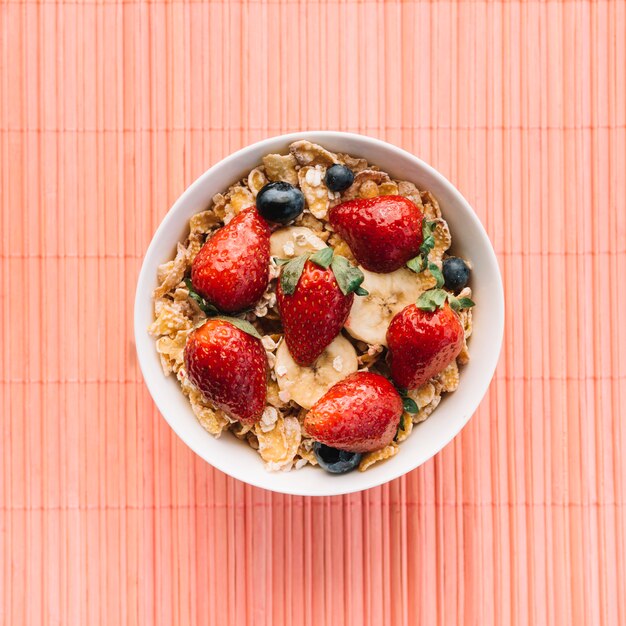 Corn flakes with berries on pink table