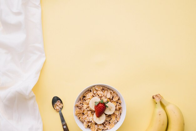 Corn flakes with with fruits in bowl on table