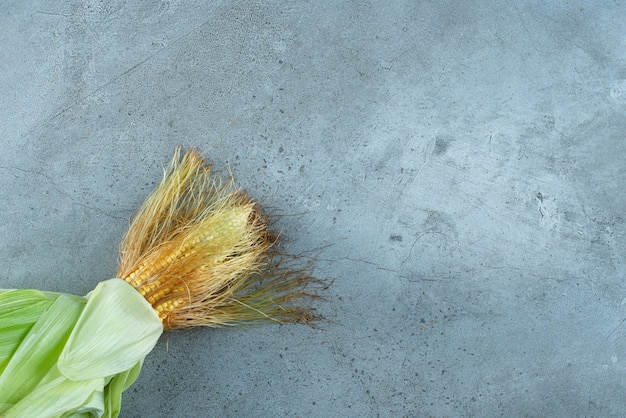 A corn plant covered with green leaves on the ground. High quality photo