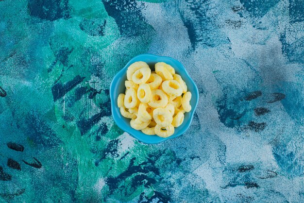 Corn rings in a bowl , on the blue table.