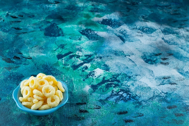 Corn rings in a bowl , on the blue table.