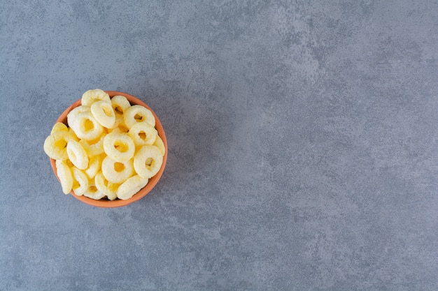 Corn rings on a clay bowl , on the marble surface