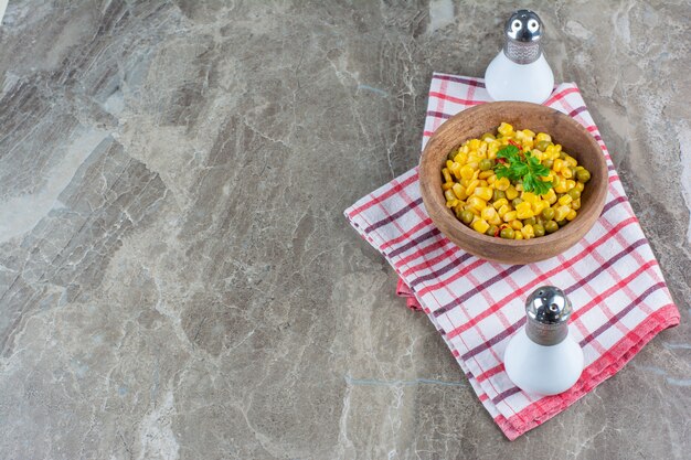 Corn salad in a bowl next to salt on tea towel on marble.