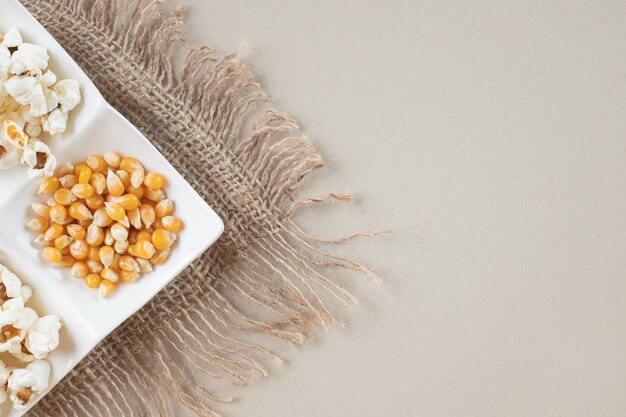 Corn seeds with popcorns in a white platter.