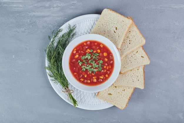 허브와 함께 하얀 접시에 토마토 소스에 옥수수 수프.