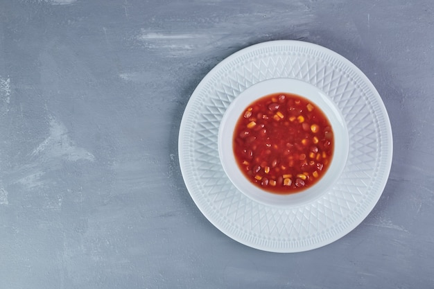 Corn soup in tomato sauce in a white plate.