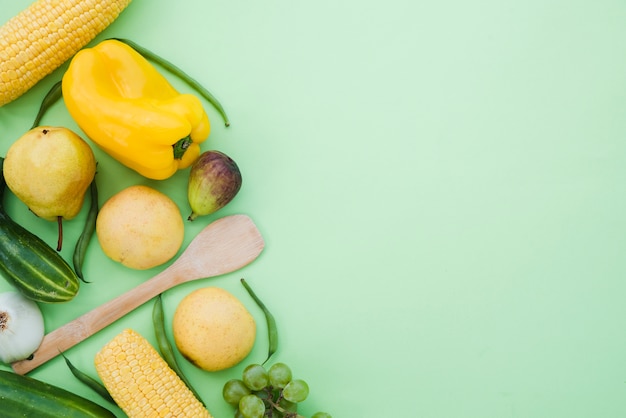 Corn; yellow bell pepper; cucumber; pears; fig; grapes and beans on mint green backdrop