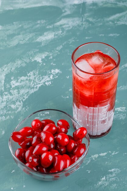 Cornel berries in a bowl with drink high angle view on plaster