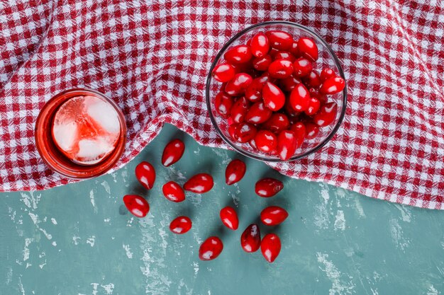 Cornel berries in a bowl with drink on plaster and picnic cloth