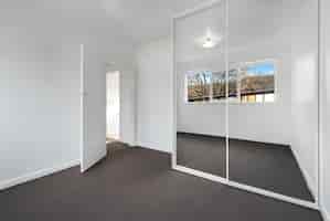 Free photo corner of an empty new room with white walls and a wardrobe with mirror sliding doors