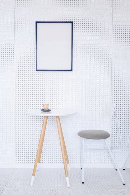 Уголок кухни со столом, серыми стульями и плакатом, висящим на светло-серой стене.