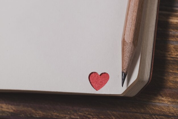 Corner of a notebook with a red heart and a pencil