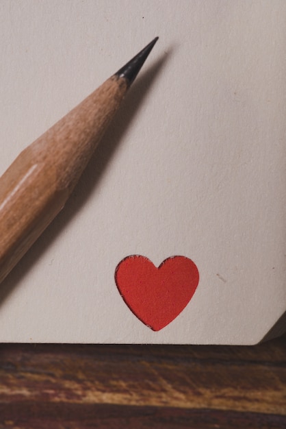 Free photo corner of a notebook with a red heart and a pencil