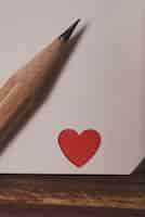 Foto gratuita angolo di un notebook con un cuore rosso e una matita