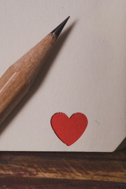 Corner of a notebook with a red heart and a pencil