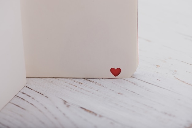 Angolo di un notebook con un cuore rosso su un tavolo di legno