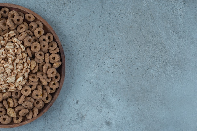 Cornflakes in the wooden plate , on the blue background.