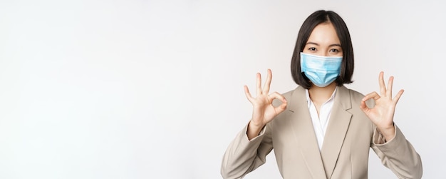 無料写真 コロナウイルスと医療マスクを示すアジアのセールスウーマン会社員の職場のコンセプト画像o