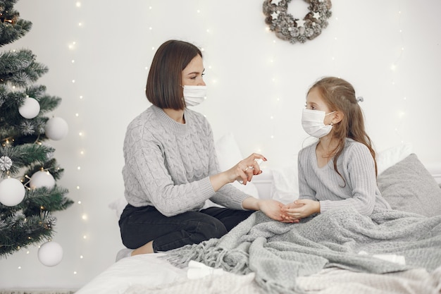 Coronavirus in a child. Mother with daughter. Child lying in a bed. Woman in a medical mask.