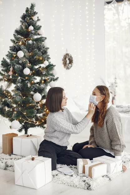 Coronavirus and Christmas concept. Woman helps her friend wearing a mask.