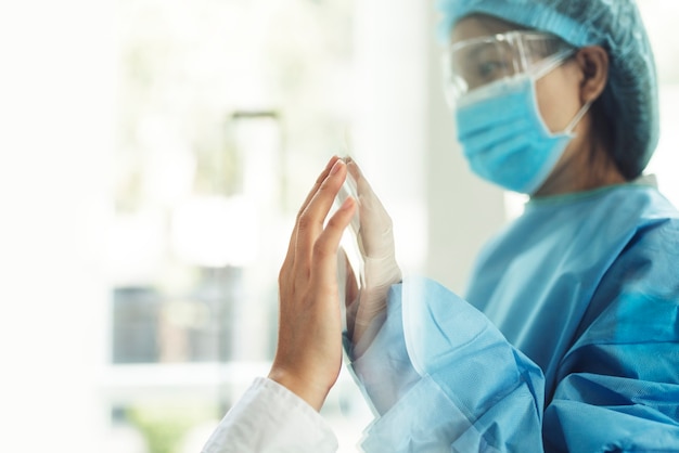 Coronavirus doctor touching family hand through a glass window