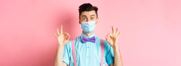 Coronavirus healthcare and quarantine concept happy guy in medical mask and festive bowtie showing a