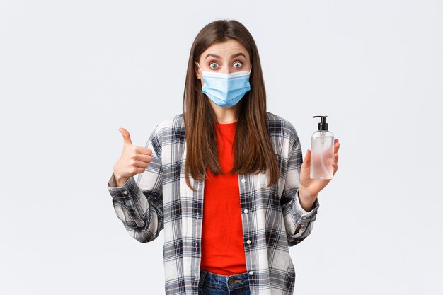 Coronavirus outbreak, leisure on quarantine, social distancing and emotions concept. Amazed and impressed girl in medical mask, want prevent catching virus, thumb-up good hand sanitizer