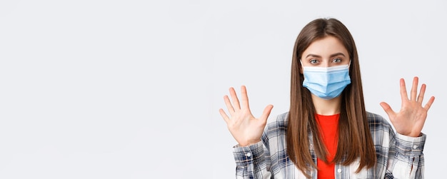 Foto gratuita tempo libero per l'epidemia di coronavirus sul concetto di distanza sociale ed emozioni in quarantena donna caucasica attraente in maschera medica mostra una quantità o una quantità di dieci dita sfondo bianco